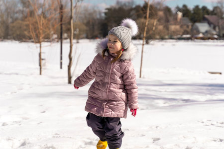happy little girl playing in the snow on a winter sunny day