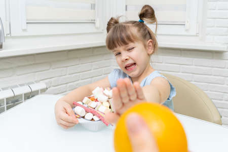 Cute little girl choosing between oranges and sweets,の写真素材