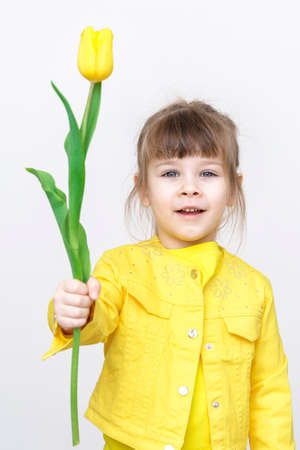 cute baby girl iwith yellow flowers on gray backgroundの写真素材