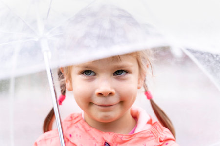 Outdoor portrait of a cute child girl under umbrella