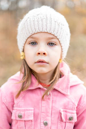 autumn portrait of a pensive caucasian little girl in a knitted hatの写真素材