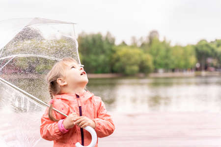 little girl opening her mouth looking at water dropletsの写真素材