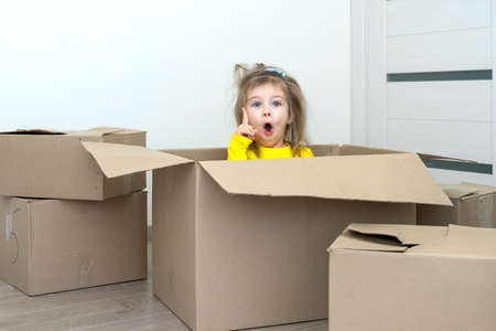 happy little girl in a cardboard box to move, finger up, idea for movingの写真素材