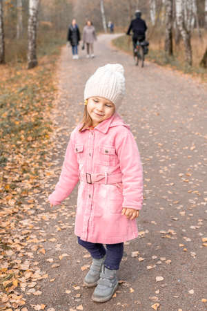 little caucasian girl on a walk in the autumn park. fall season concept.の写真素材
