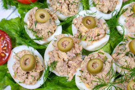 Stuffed eggs with tuna with green vegetables and olivesの写真素材
