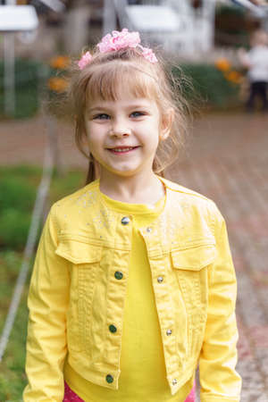 portrait of smiling little girl in yellow jacket outdoors.の写真素材