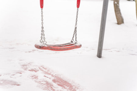 empty baby swing covered with snow in the playground.の写真素材