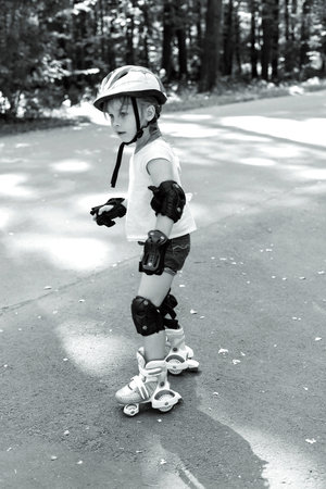 Kid in protective sportswear. black and white photo. little girl is rollerblading in the park.
