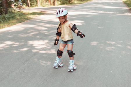 Little pretty girl on roller skates in helmet at a park. .baby in protective sportswear
