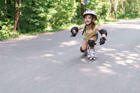baby in protective sportswear. little girl learning to roller skateの写真素材