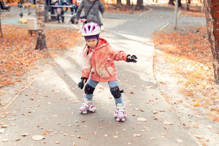 5 year old little girl roller skating in autumn parkの写真素材