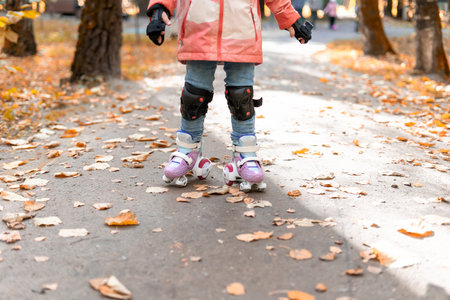 5 year old little girl roller skating in autumn park