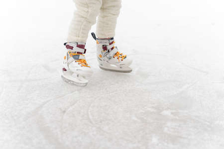 child is skating on the rink, legs close-up and place for textの写真素材
