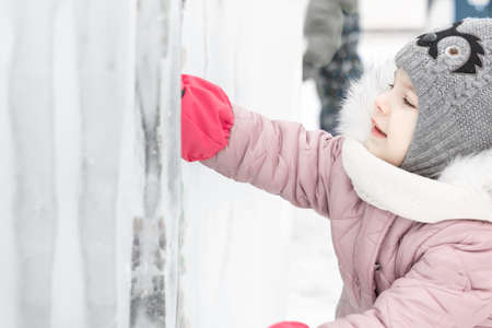 little cute girl explores the ice fortress in winter.の写真素材