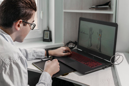 Young student male 3D designer uses graphics tablet to work at his desk. development of 3d characters for online games.の写真素材