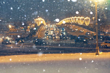 Falling snow against the backdrop of cars with headlights on at night in the center of Moscow. The concept of the first snow or snowfall in winter.の写真素材