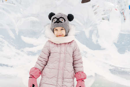 little girl in a knitted hat and scarf and ice sculpturesの写真素材