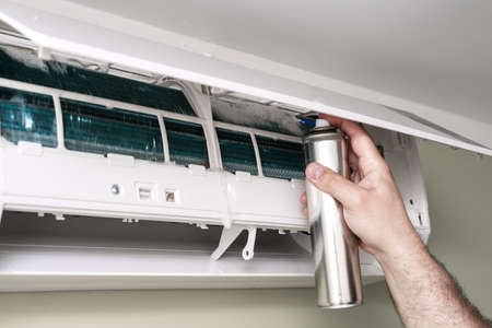 man master installer working and cleaning air filter on a indoor unit air conditioner at client's home with antibacterial spray.の写真素材