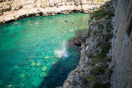 Beautiful beach with people in Polignano a Mare in the southern part of Italy crystal clear azure waterの写真素材