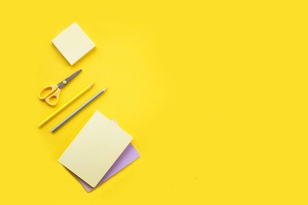 Different stationery on the yellow background notebooks, pencils and yellow stickers with the yellow and metallic scissorsの写真素材