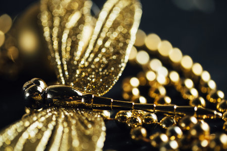 Black and gold abstract background with artificial dragonfly and garlands closeupの写真素材