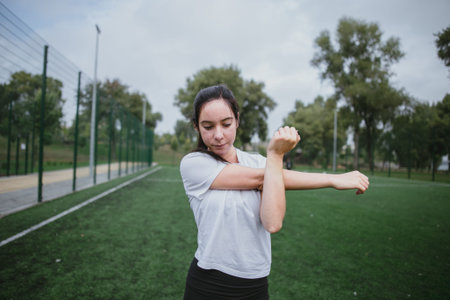 Young woman do the workout plays sports in the park outside playground