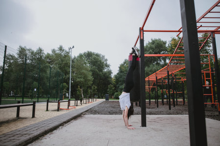 A young woman does the handstand on the playground in the park outdoors
