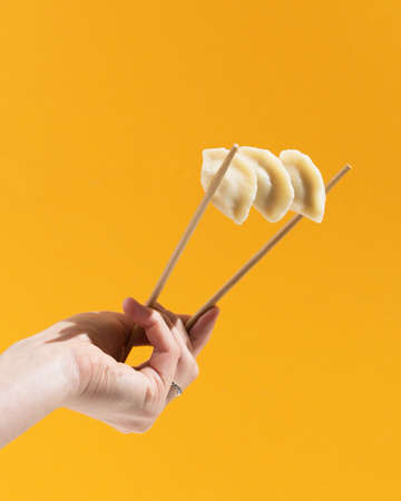 Chinese dumplings jiaozi on the orange background traditional food concept chopsticksの写真素材