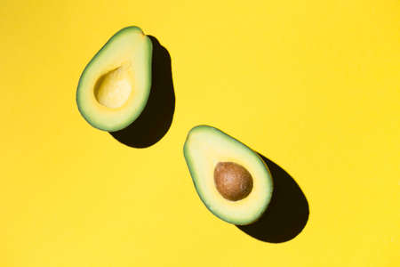 Cut avocado on the yellow backdrop keto dietの写真素材