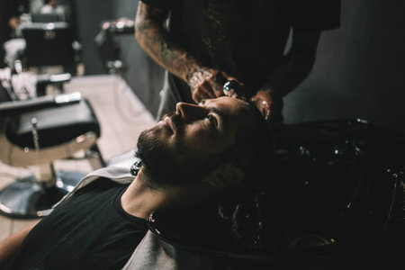 Young man client at barbershop getting haircut hipster washing hair