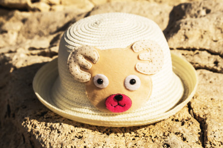 a kid hat from the sun in the form of a bear bear lying on a rock on the beach, beach concept.の写真素材