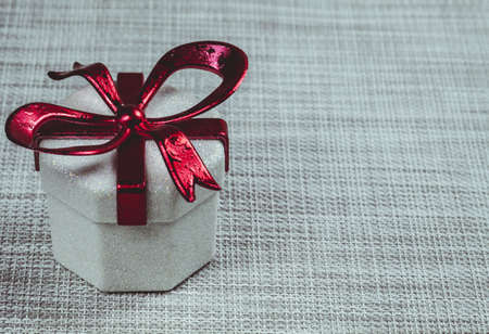 Gift box with a red ribbon on a grey background.の写真素材