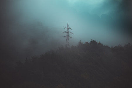 the power line is high in the mountains in the fog at sunset before the storm, blurred