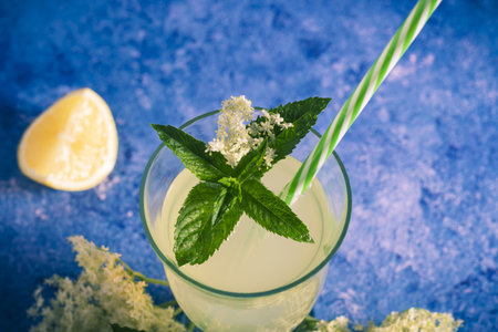 Elder lemonade - healthy and refreshing summer drink. Close up of homemade elderflower syrup in a glass with elder flowers. Summer drink Hugo Champagne drink with elderflower syrup, mint and lime.の写真素材
