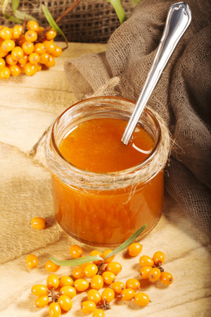 Homemade jam. Glass jar with sea buckthorn jam on canvas background. Source of vitamins in autumn...