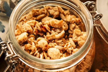 Homemade granola with nuts and seeds in glass jar on a wooden background for healthy breakfast....