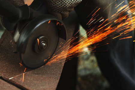grinding cutting metal sheet with angle grinder machine and sparks, Close up.の写真素材