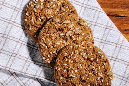 Homemade oatmeal cookies with seeds on natural linen napkin on wooden background. Healthy Food Snack...