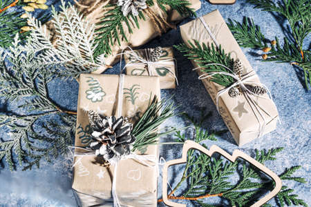 Christmas presents with gift box decorated with pine cones and twigs on blue background, preparation for holidays. Christmas presents and New Year. Handmade. Selective focus.の写真素材