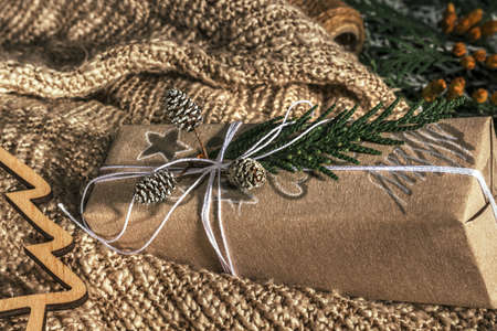 Christmas presents with gift box decorated with pine cones and twigs on on a cotton fabric background, preparation for holidays. Christmas presents and New Year. Handmade. Selective focusの写真素材
