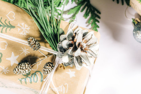Christmas presents with gift box decorated with pine cones and twigs on a white background,...