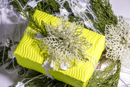 Christmas composition. Gift, fir tree branches, white decoration on yellow gift box. Christmas,...