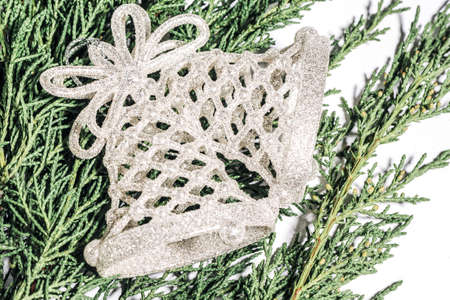 Silver Christmas bell on a branch of a coniferous tree, Christmas, winter, new year concept.の写真素材
