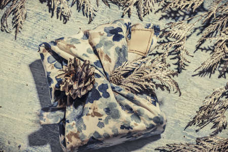 Zero waste gift wrapping traditional Japanese furoshiki style. Blue hand made gift package for Christmas with fabric thuja and cone. Ecological concept eco-friendly decor xmas. Close upの写真素材