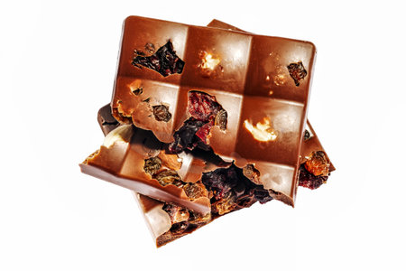 Hazelnut and dried fruits dark chocolate pieces tower isolated on white.