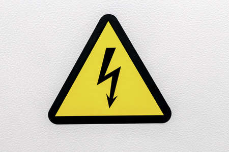 Yellow sigh danger electric shock with lightning in triangle on a metal door. Danger Electrical Hazard High Voltage Sign. Close up.の写真素材