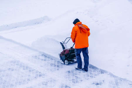 Man with motorized track drive snowblower clears snow, a snowblower on a snowy road detail. Motor machine for removing wet, heavy snow. Snowthrower equipmentの写真素材