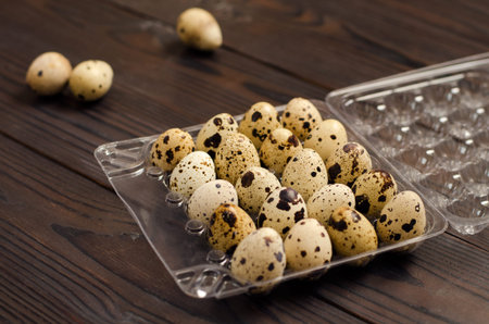 Quail eggs in a plastic container on a dark wooden background. Close upの写真素材