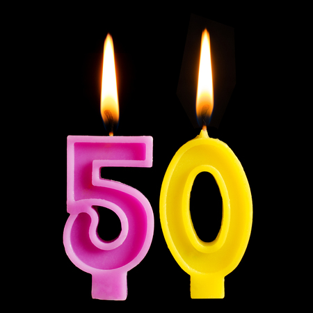 Burning birthday candle in the form of 50 fifty figures for cake isolated on black background. The concept of celebrating a birthday, anniversary, important date, holiday, table settingの写真素材