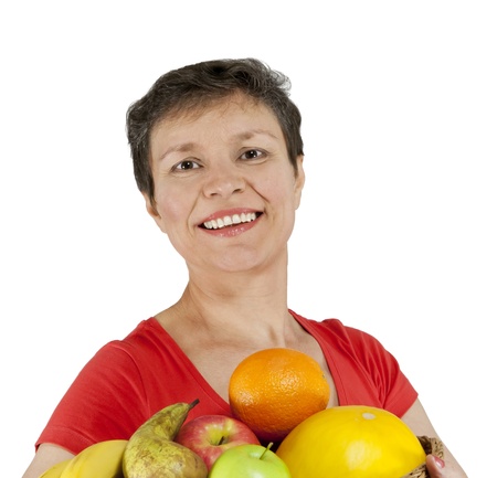 A happy smiling middle-aged woman holding a basket full of fruits  Isolated over white の写真素材